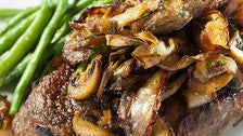 Prime ribeye topped with mushrooms and onions at 555 East American Steakhouse