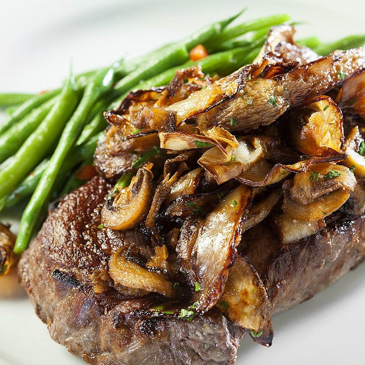 Prime ribeye topped with mushrooms and onions at 555 East American Steakhouse